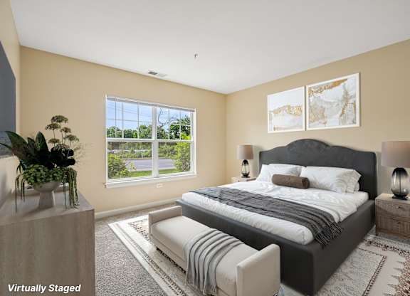 A bedroom with a large bed and a window overlooking a green area.