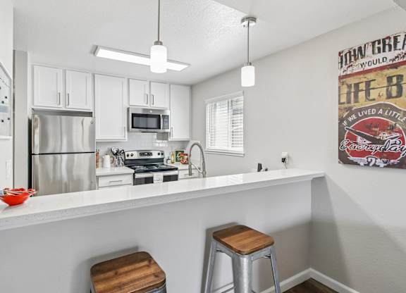 A kitchen with white cabinets and a fridge.