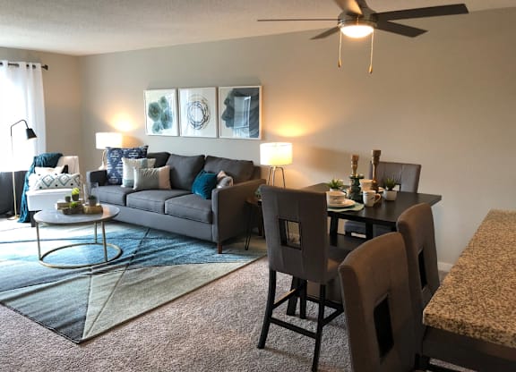 A living room with a grey couch, a coffee table, and a dining table with chairs.