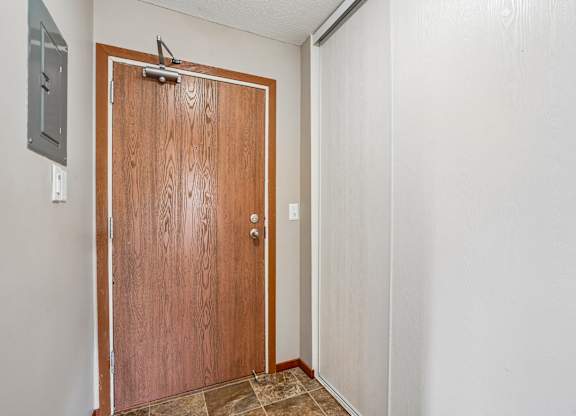 A brown door with a silver handle is in a room with white walls.