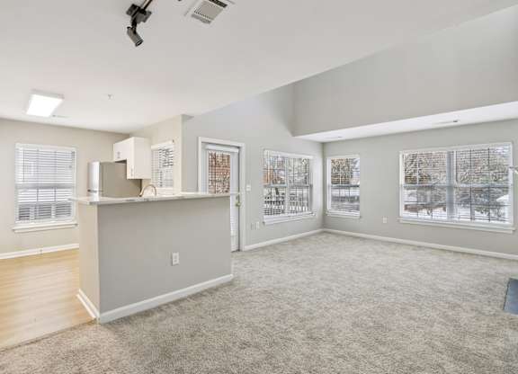 A spacious living room with a kitchenette and a large window.