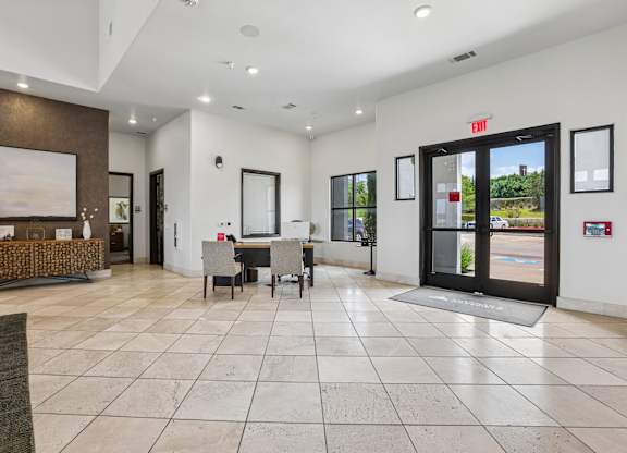 A spacious lobby with a reception desk and a view of the outdoors through a glass door.