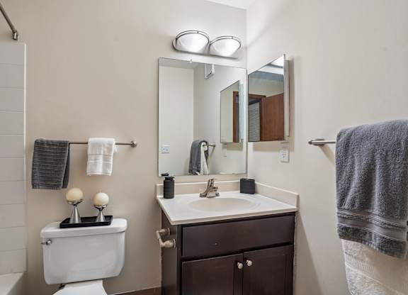 A bathroom with a toilet, sink, mirror, and towel.