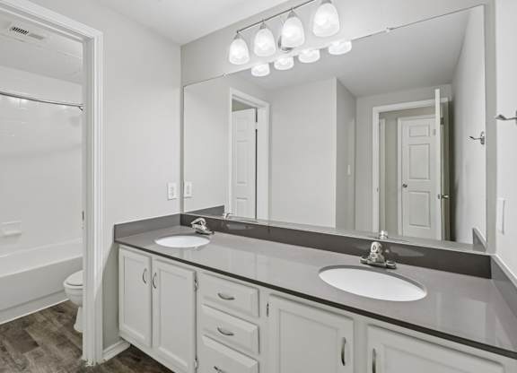 A bathroom with a sink, mirror, and a tub.