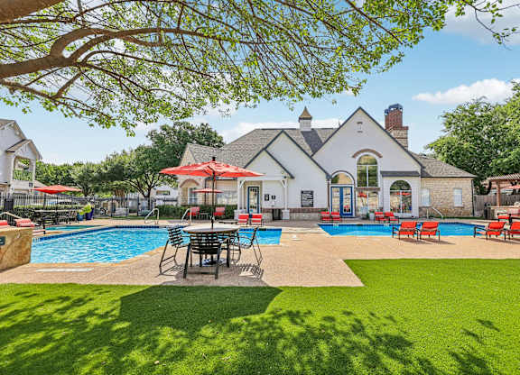 A large house with a pool and lawn chairs.