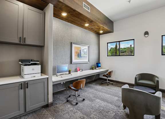 A room with a desk, chairs, and a printer.