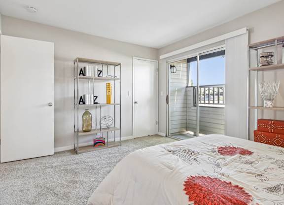 A bedroom with a bed, a shelf with letters, and a balcony.