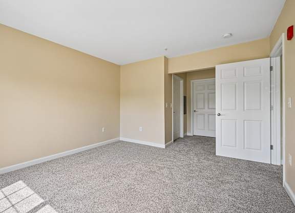 A room with a carpeted floor and a white door.