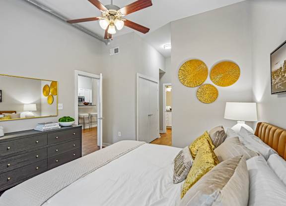 A bedroom with a white bed and a ceiling fan.