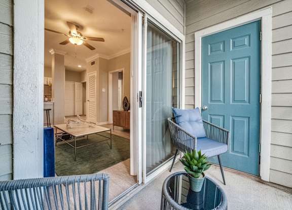 a porch with a blue door and a chair and a table