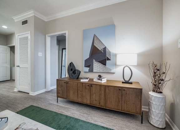 an open living room with a wooden dresser and a table with a lamp