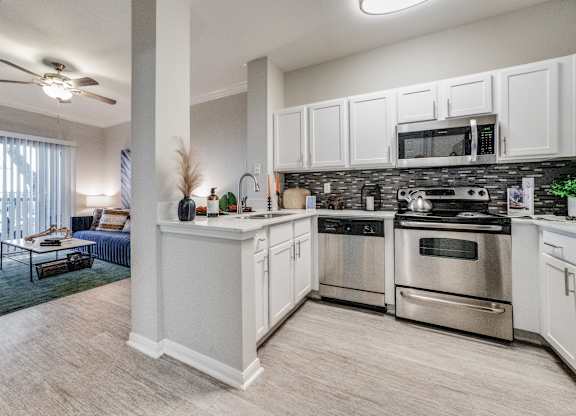 spacious kitchen with stainless steel appliances and white cabinets in an apartment
