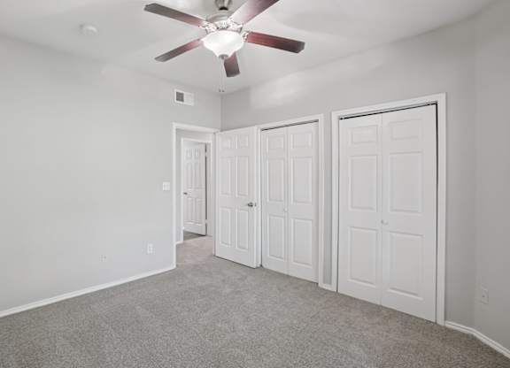 A room with a ceiling fan and three doors.