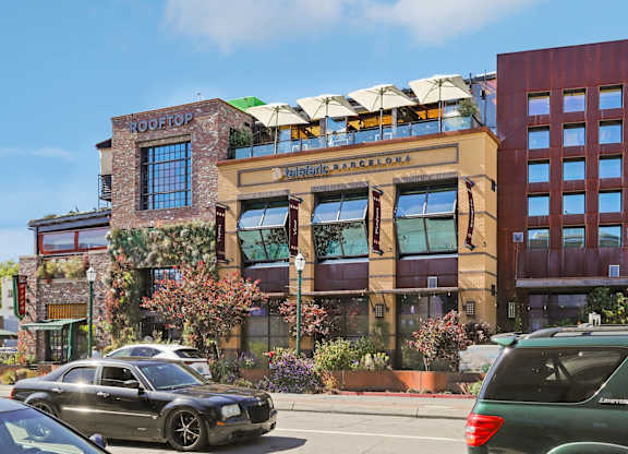 A black car is parked in front of a building with a sign that says Rooftop.