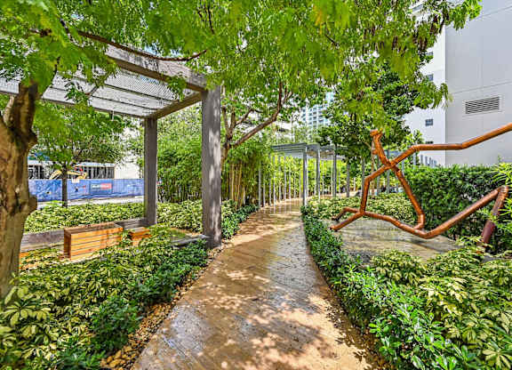 A walkway in a park with a bench and a sculpture.