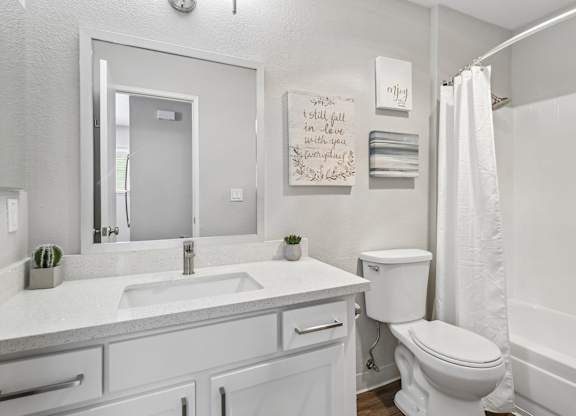 A white bathroom with a toilet, sink, and mirror.