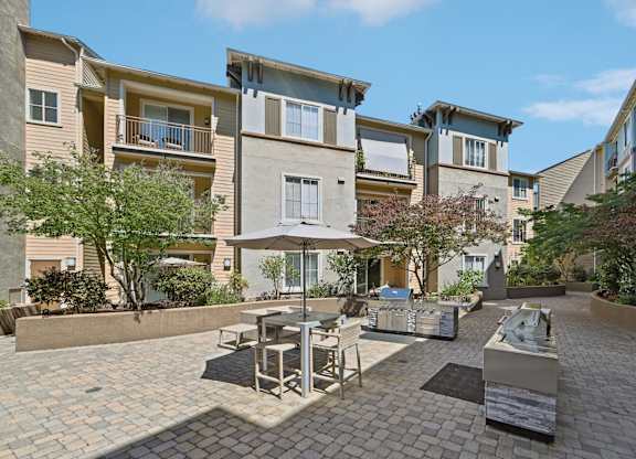 A patio with a table and chairs is surrounded by apartment buildings.