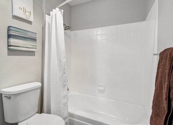 A white toilet sits next to a white bathtub in a bathroom.