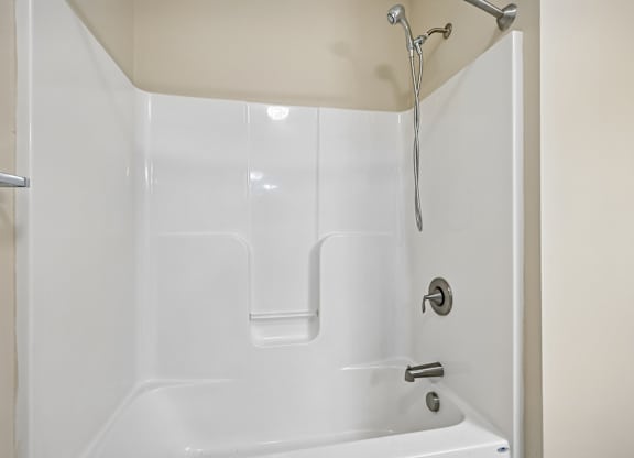 A white bathtub with a shower head and faucet.