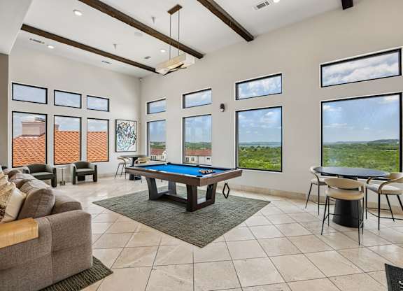 A large room with a pool table and a view of the outdoors.