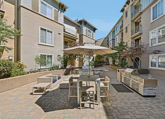 A patio with a table and chairs is surrounded by apartment buildings.