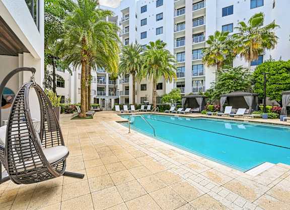 A chair is on a patio next to a pool.