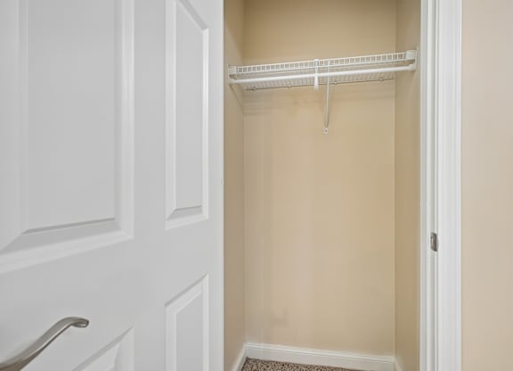 A white closet with a shelf and a white door.