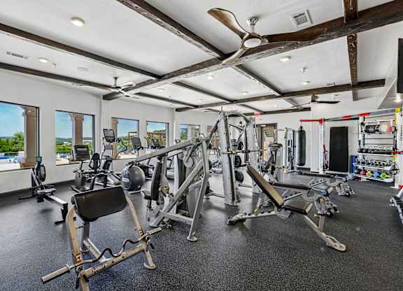 A spacious gym with a variety of equipment and a view of the outdoors through large windows.