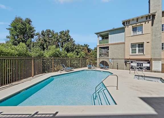 A swimming pool in front of a building with a fence around it.