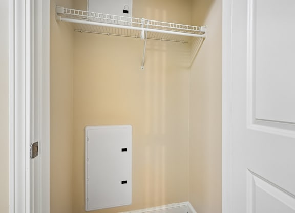 A white metal shelf is mounted on a wall.