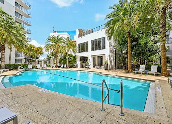 A swimming pool surrounded by palm trees and lounge chairs.