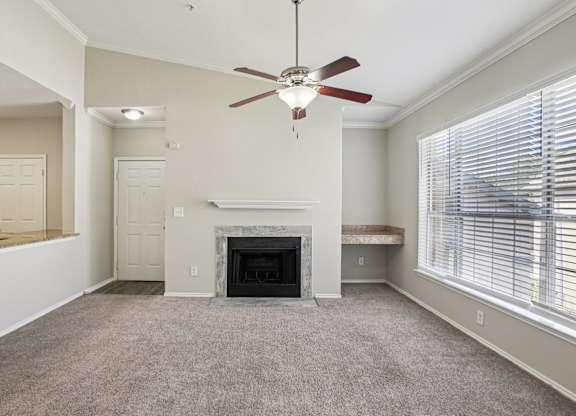 A living room with a fireplace and a ceiling fan.