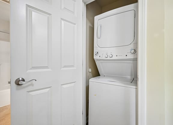 A white door is open to reveal a white microwave and oven.