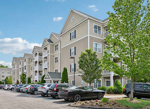 A parking lot in front of a building with cars parked.