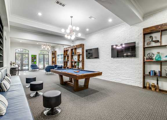 A room with a pool table and a television mounted on the wall.