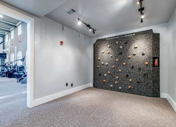 A room with a climbing wall and a gym in the background.