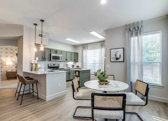 A kitchen with a table and chairs in front of a window.