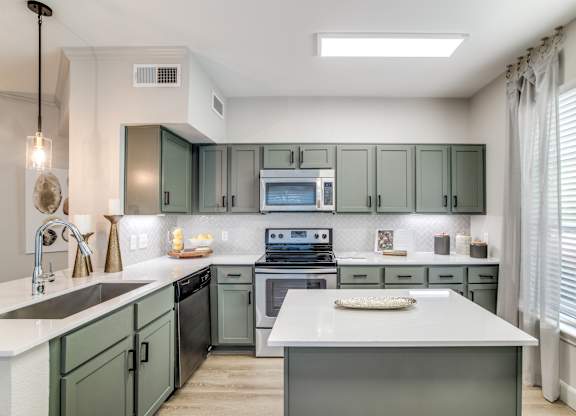 Washington Avenue Coalition, TX, Luxury Apartments Near Rice University - Marcella Memorial Heights - A Kitchen With Sage-Green Cabinetry, Stainless Steel Appliances, And A Large Window.