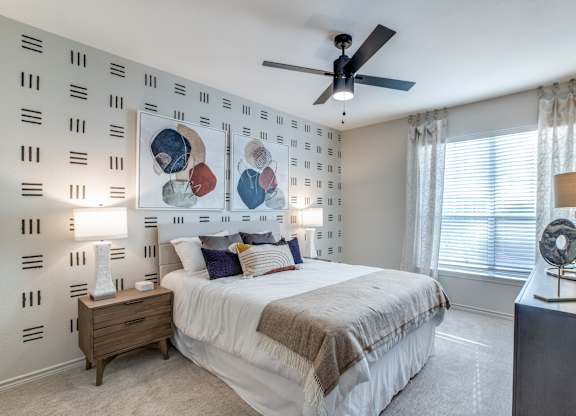 Dog-Friendly Luxury Apartments In Washington Avenue Coalition, TX - Marcella Memorial Heights - A Bedroom With Two Matching Bedside Tables, Ceiling Fan, And A Large Window.