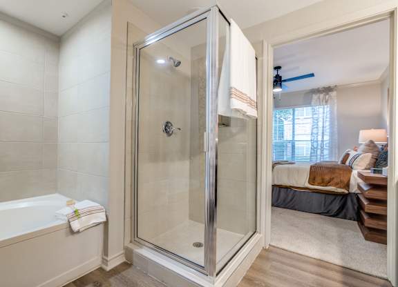 A bathroom with a glass shower door and a white bathtub.