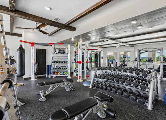 A gym with a variety of equipment including dumbbells, weight machines, and a bench press.