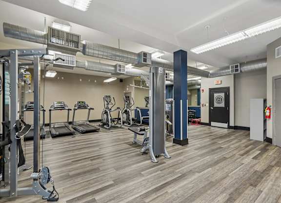 A gym with a variety of equipment including treadmills, weights, and exercise machines.
