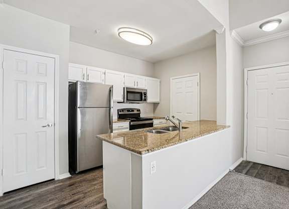 A kitchen with white cabinets and a granite countertop.