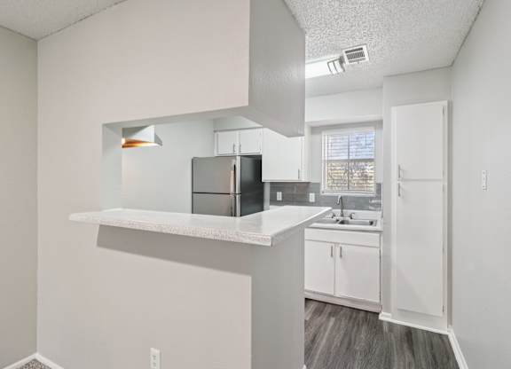 A kitchen with white cabinets and a black refrigerator.