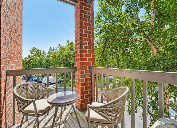 A balcony with a table and chairs overlooking a tree.