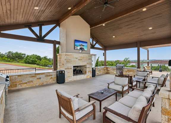 A patio with a fireplace and chairs.