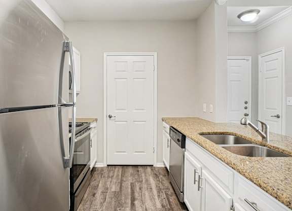 A kitchen with a stainless steel refrigerator and white cabinets.