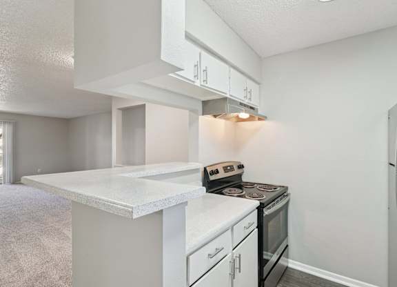 A kitchen with a white countertop and black appliances.