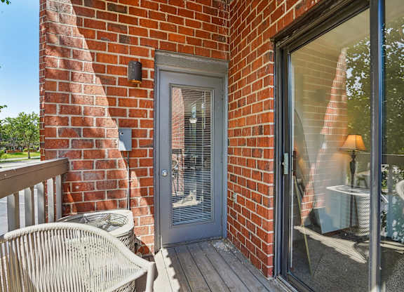 A patio with a chair and a table is visible through a glass door.