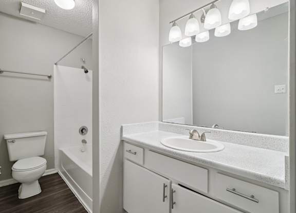 A white bathroom with a toilet, sink, and mirror.